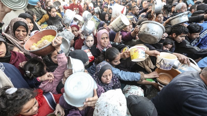 A charity organisation distributes meals to displaced Palestinians at the Nuseirat Refugee Camp