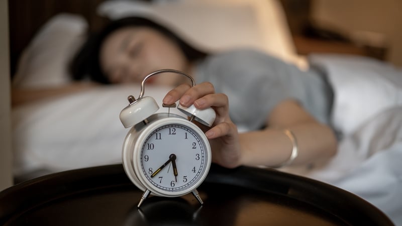 A young Asian woman presses her alarm clock in bed (Image: Getty Images)