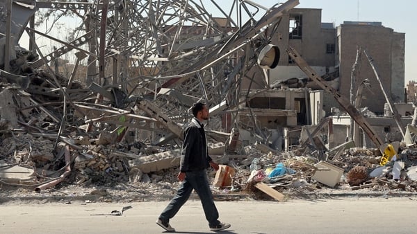 A man walks past destroyed buildings following airstrikes in central Tehran