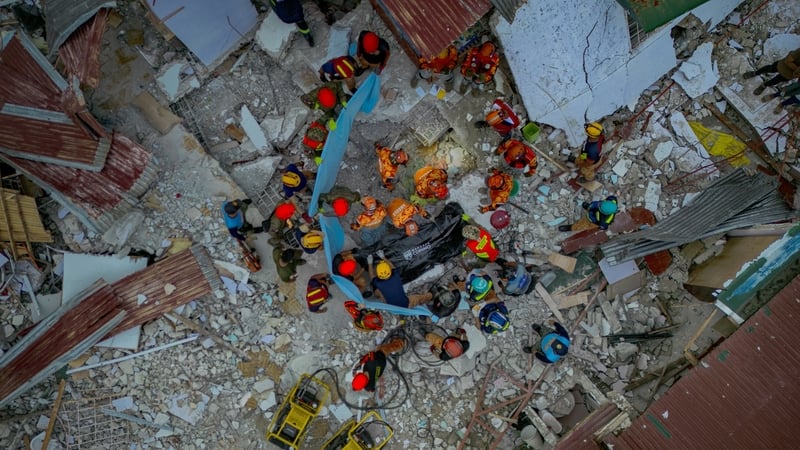 overhead view of rescue workers retrieving a body from rubble of a building