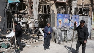 Shop owners clean up the rubble caused by missile explosion in the vicinity of a building in south-east Tehran