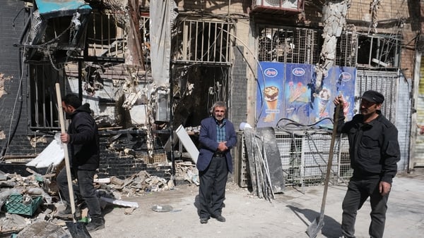 Shop owners clean up the rubble caused by missile explosion in the vicinity of a building in south-east Tehran