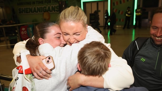 Dymphna Mackin with her husband Hugh Mackin embraces her children as she arrives at Dublin Airport