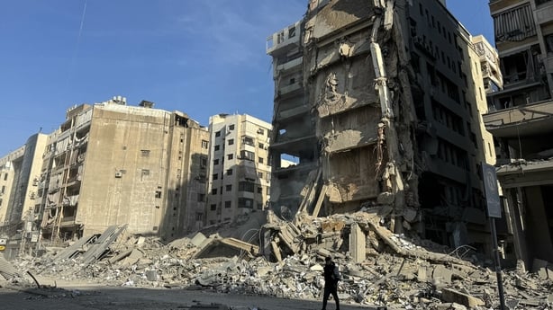 A man walks by rubble from a damaged building