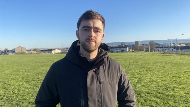 Councillor Conor Reddy standing in a field in a black jacket looking sternly at the camera