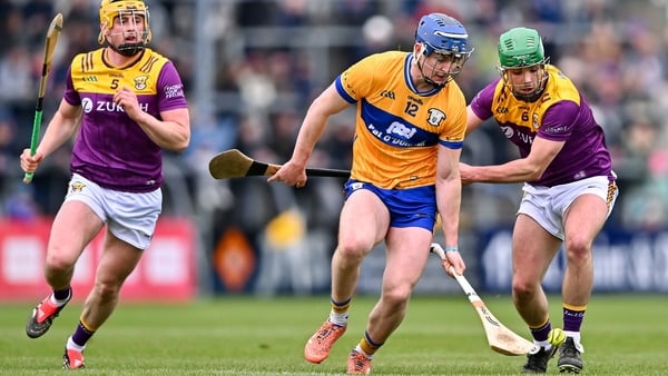 8 March 2026; Jack O'Neill of Clare takes on Wexford players Richie Lawlor, left, and Damien Reck during the Allianz Hurling League Division 1B match between Clare and Wexford at Zimmer Biomet Páirc Chíosóg in Ennis, Clare. Photo by Piaras Ó Mídheach/Spor