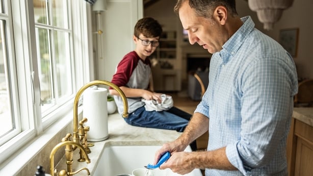 Father and son washing dishes together in kitchen
