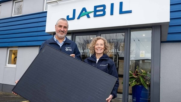 Migdo Natal and Orla Stevens hold a solar panel outside the Jabil premises