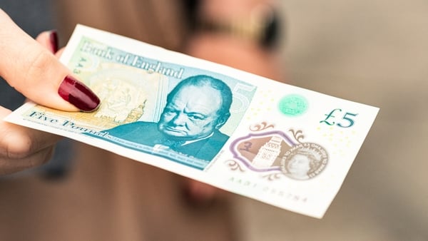A woman holds a Bank of England five pound note, featuring former British Prime Minister Winston Churchill