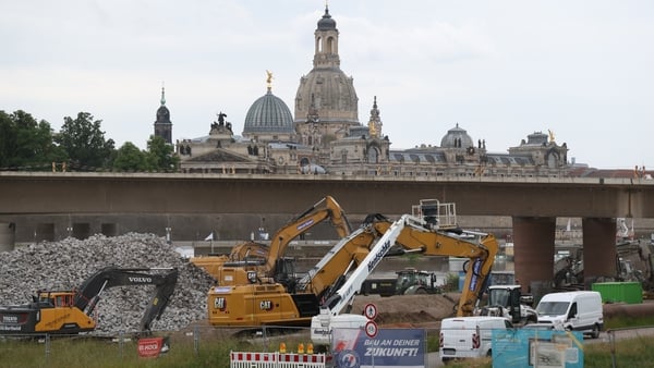construction equipment is seen close to a bridge with a historic building in the background