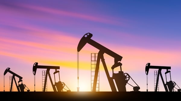 Silhouettes of oil pumpjacks operating in an oil field at sunset. Concept of crude oil extraction, energy production, and the petroleum industry.