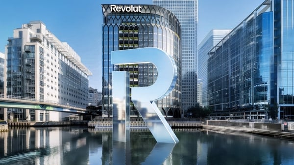 Image of a giant R standing on water in front of an office building with Revolut signage
