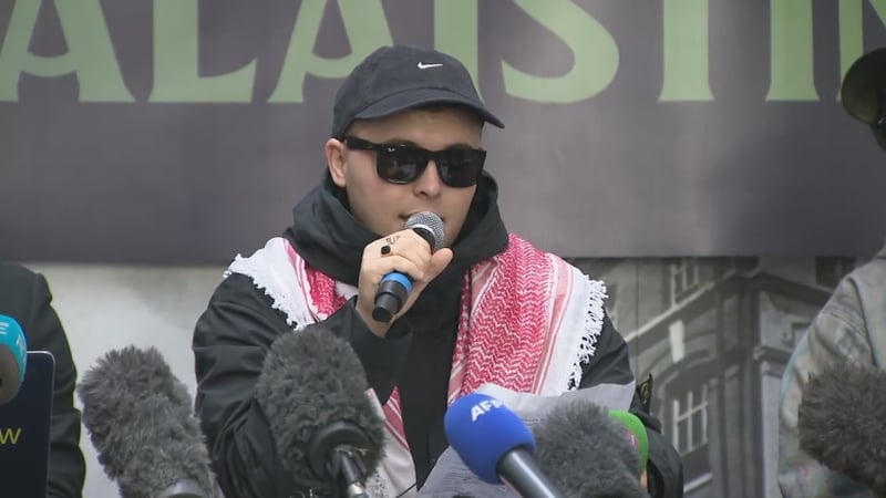 Liam Óg Ó hAnnaidh ag labhairt leis na meáin agus le lucht tacaíochta Kneecap ag preasócáid i mBéal Feirste inniu