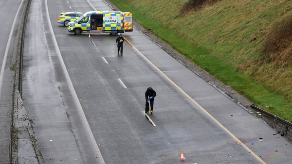 two garda vehicles and two people in garda uniforms are seen measuring a roadway