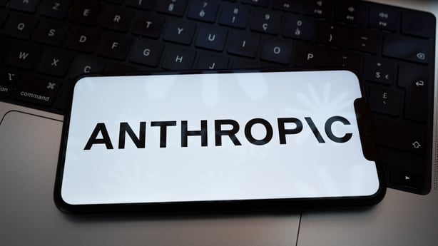 The Anthropic logo appears on the screen of a smartphone placed on a laptop keyboard.