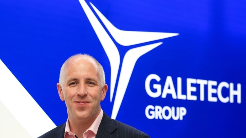 A business man poses in front of Galetech Group signage
