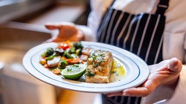 Close-up on a waitress serving a plate of food at a restaurant – food service concepts 