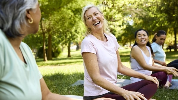 Happy woman enjoying yoga with friends in park
