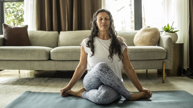 Senior woman doing yoga inside home
