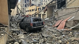 Debris is strewn along a street and vehicles after a residential apartment block was struck in an Israeli airstrike in Beirut