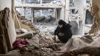 woman sifts through the rubble in her house in the Beryanak District in Tehran