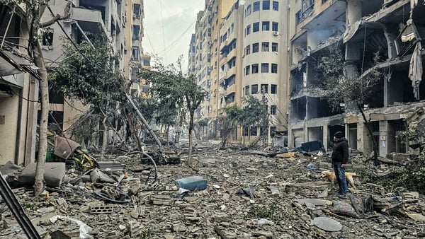 A man and his dog walk across the rubble of a building at the site of an Israeli airstrike in Beirut’s southern suburb Haret Hreik