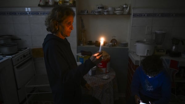 A woman holds a candle while a boy checks his cellphone during a blackout in the Luyano neighborhood of Havana on January 28, 2026. (Photo by YAMIL LAGE / AFP)
