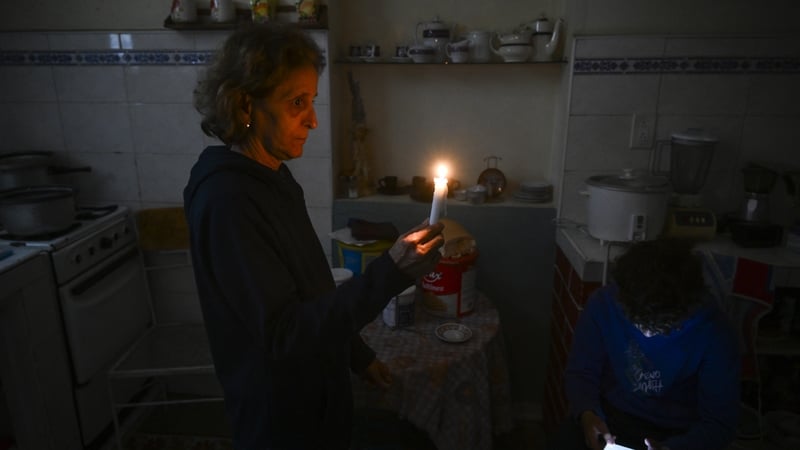 A woman holds a candle while a boy checks his cellphone during a blackout in the Luyano neighborhood of Havana on January 28, 2026. (Photo by YAMIL LAGE / AFP)