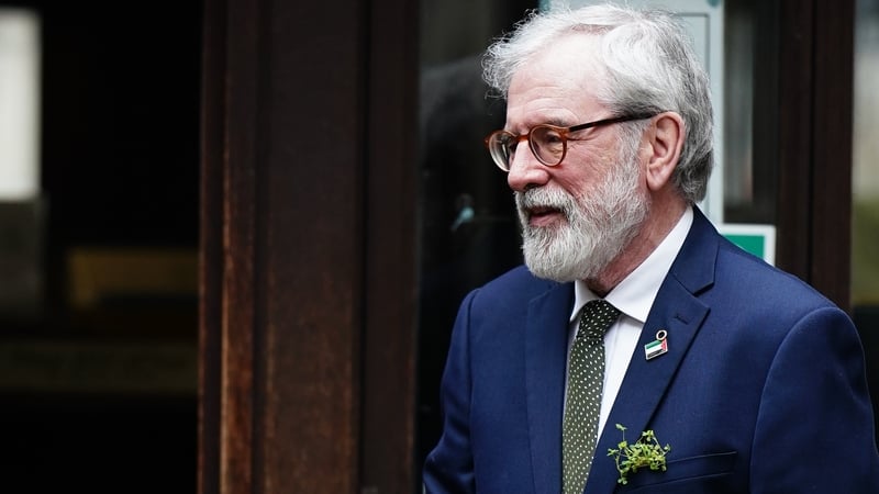 a photograph of Gerry Adams, wearing a sprig of shamrock on his jacket, outside the high court in London