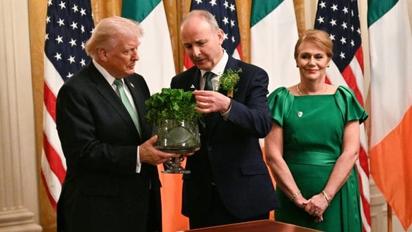 Taoiseach Micheal Martin (C) presents US President Donald Trump with a bowl of shamrock at The White House as Mr Martin's wife Mary O'Shea looks on