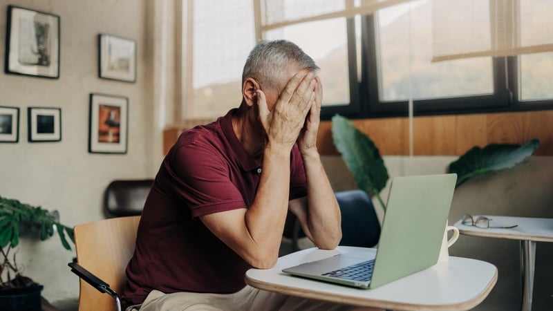 Tired mature man uses laptop