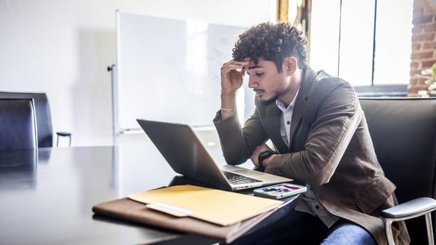 Young businessman working on laptop and looking worried in modern office conference room