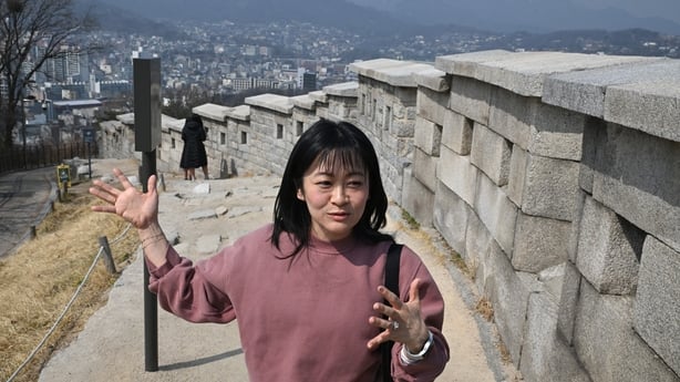 Emily Han speaks in front of the fortress wall during a street interview with AFP at Naksan Park in Seoul on 17 March, 2026. (Photo by Jung Yeon-je / AFP) / TO GO WITH AFP STORY