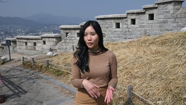 Nhung Nguyen speaks in front of the fortress wall during a street interview with AFP at Naksan Park in Seoul on 17 March, 2026. (Photo by Jung Yeon-je / AFP) / TO GO WITH AFP STORY SKorea-tourism-entertainment-animation BY Kang Jin-kyu