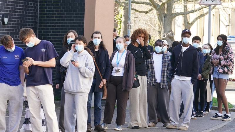 Students wait in line at the entrance to the sports hall at University of Kent campus in Canterbury