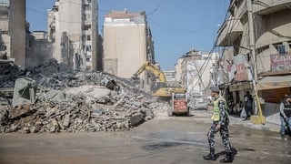 A policeman walks past the remains of a building in Bachoura, which was hit by an Israeli airstrike