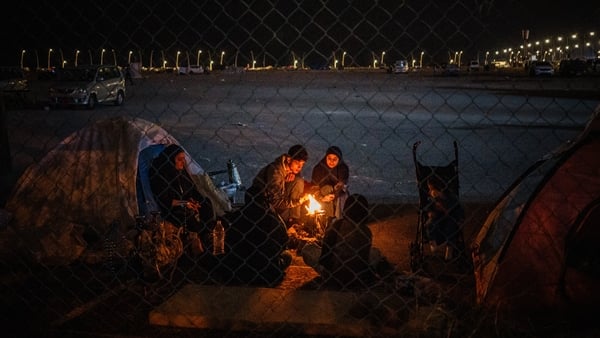 Displaced family members sit around a fire outside their tent along the seafront in Beirut on March 1
