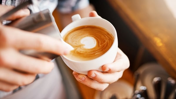 A cropped shot of an unrecognizable barista pouring frothy milk into a cup of hot coffee turning it into a picture