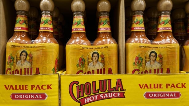 Bottles of hot sauce stacked on a shop shelf