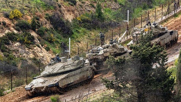 Israeli soldiers try to tow a tank stuck in the mud on the Israeli side of the border with Lebanon