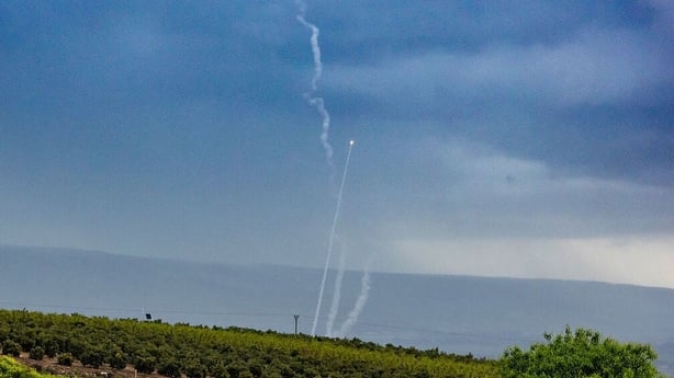 Iron Dome interceptors go up behind a group of Israeli soldiers along the border with Lebanon,