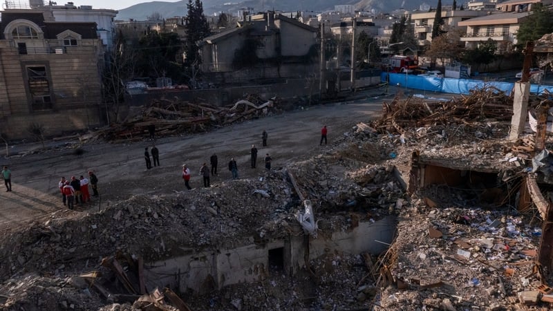 Civilians and emergency workers look upon the remains of a residential and commercial building in the Shahrak-e Gharb neighbourhood of Tehran, Iran