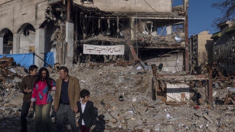 Civilians walk near the remains of a residential and commercial building in the Shahrak-e Gharb neighbourhood of Tehran, Iran