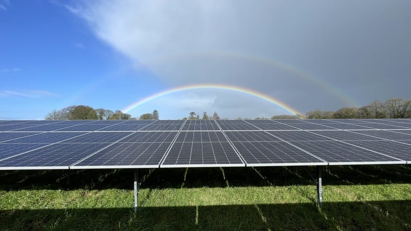 Image of a solar farm in a field with a rainbow in the background