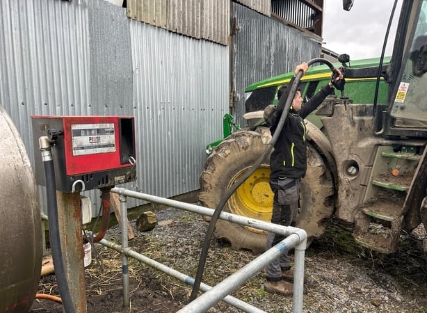 A farmer adding fuel to a tracker