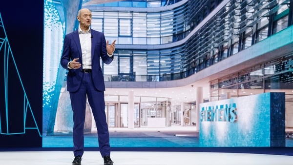 A business man stands on a high-tech stage with Siemens signage to the side