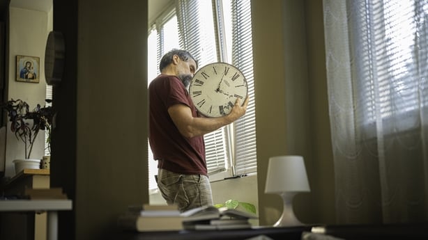 Mature man over 50s arranging his wall clock