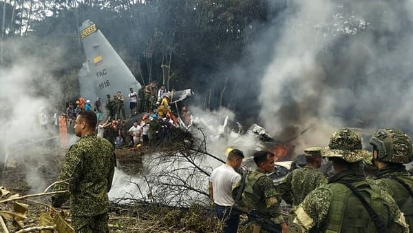 Soldiers and rescuers near an Air Force Hercules emitting thick smoke after the aircraft crashed during takeoff in Puerto Leguizamo