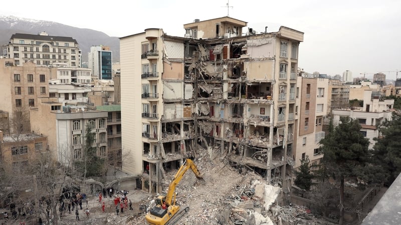An excavator clears rubble from destroyed residential buildings in northern Tehran on March 23, 2026