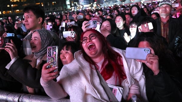 BTS fans react as they watch the comeback concert of K-pop boy group BTS on a screen at the venue in Seoul on March 21, 2026. South Korean megastars BTS reunited on 21 March for their first show in nearly four years. (Photo by Jung Yeon-je / AFP)